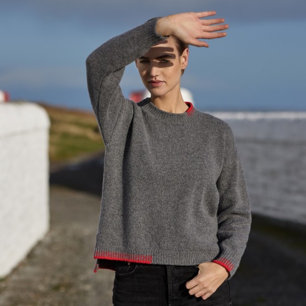 Grauer irischer Wollpullover mit farbigen Applikationen am Bündchen. Von Fisherman out of Ireland.